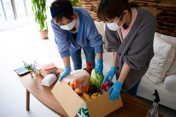食料物資が入った箱を確認するルームメイトの女性たち
