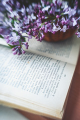 Naklejka na ściany i meble selective blurred focus. An old vintage battered open book with text in Russian and fresh blooming violet lilac