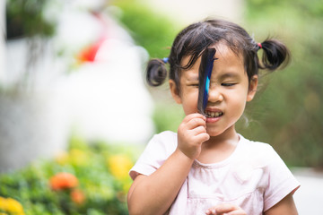 Obraz premium Cute little girl playing with bird feather outdoor.