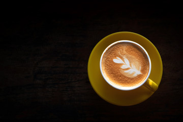 Cup of coffee with latte art on wooden table and copy space; top view.