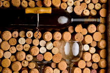 Wine corks of different sizes, a corkscrew, a bottle of wine and a glass shot on an old wooden...