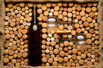 Wine corks of different sizes, a corkscrew, a bottle of wine and a glass shot on an old wooden...