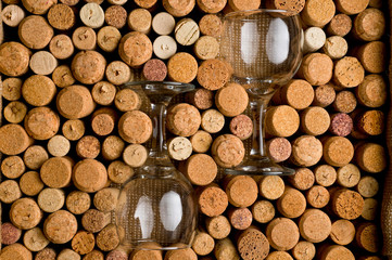 Wine corks of different sizes and a glass goblet on an old wooden surface.