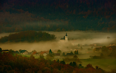 Fototapeta na wymiar sunrise on the hill where the church is between the trees and the fog completes the panorama
