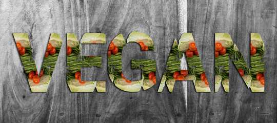 Fototapeta premium Word Vegan made from fresh vegetable cabbage, green beens, tomato and chilli on wooden Background