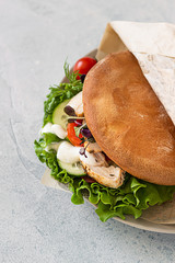 Pita bread sandwich with fresh vegetables and roasted chicken. Light grey stone background. Healthy snack. Takeaway food, street fast food.
