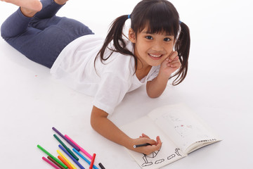 Cute little girl doing homework, reading a book, coloring pages, writing and painting. Children...