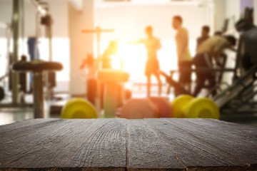 Empty wooden desk space over  blur fitness gym background. For product display montage. Business presentation.