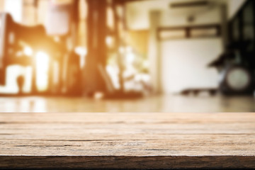 Empty wooden desk space over  blur fitness gym background. For product display montage. Business presentation.