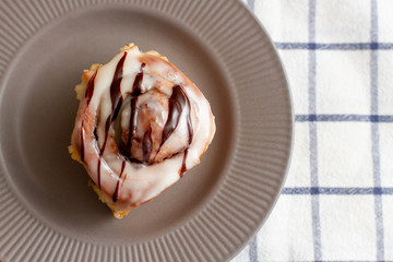 Cinnamon roll buns in ceramic plate on a checkered napkin