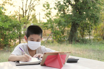 Thai children sit online learning at the front garden.