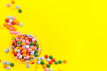 Color candy on yellow table top-down copy space