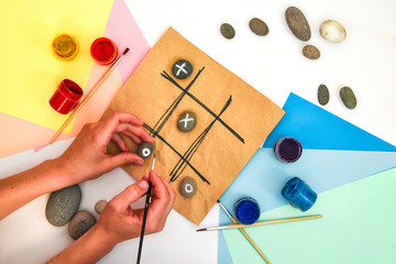 top view of tic tac toe game with stones marked with naughts and crosses. Children's art project, a...