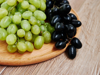 Red and green wine grapes on wooden background, dark and green organic wine grapes. Healthy fruits.