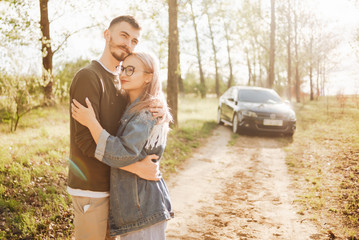 Couple walking in the woods, in the background you can see the car