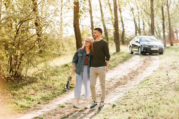 Fototapeta premium Couple walking in the woods, in the background you can see the car