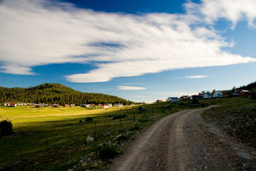 Fototapeta na wymiar country road in the countryside, mountain landscape with blue sky and clouds