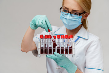 medical doctor nurse woman wearing protective mask and gloves - holding rack with virus blood tests