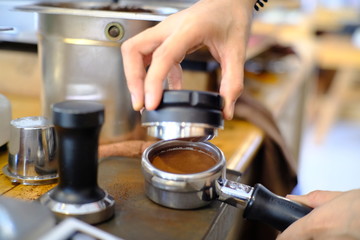 Barista woman holding coffee holder with ground coffee in one hand