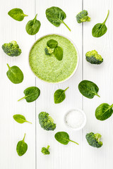 Broccoli and spinach cream soup on white desk top view. Vegetable pattern