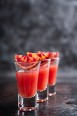 Strong red cocktail in shots on the rustic background. Selective focus. Shallow depth of field.