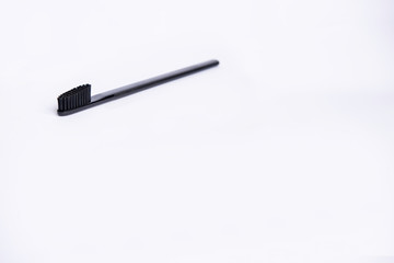 Black stylish flat strict toothbrush lies diagonally on a light background on the top of the frame