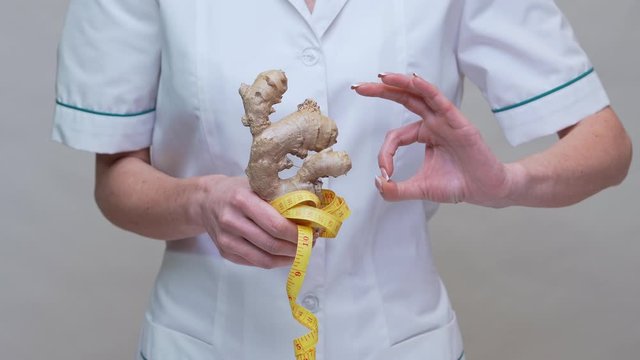 nutritionist doctor healthy lifestyle concept - holding ginger root and measuring tape