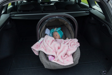 Baby girl sleeping in a safety child car seat. 3 months old baby girl. Protection concept, safety, and security.