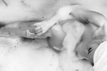 Junge Frau in der Badewanne mit viel Schaum Handtuch auf dem Kopf, Rasierer, rasiert sich die Beine, Jung, blond , schön, beauty