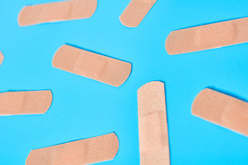 Scattered sticky medical patches on blue background. Healthcare concept