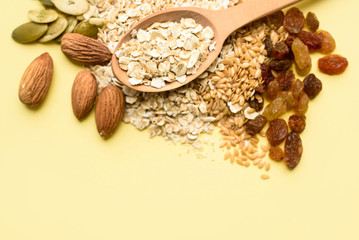 Two spoons of different sizes are filled with oatmeal and golden flax, raisins, almonds, pumpkin seeds. Healthy breakfast, proper nutrition, diet.