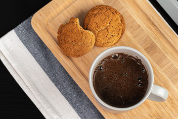 Cup of hot coffee on wooden board on kitchen table close up