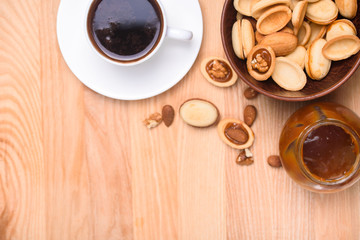 Homemade Russian nuts with condensed milk on a light pink background, wafer napkin. Cut nuts with condensed milk. Bitten goodies for coffee. Condensed Nuts. Flat lay