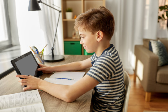 children, education and technology concept - student boy with tablet computer learning at home