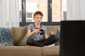 people and childhood concept - boy with remote control watching tv girl sitting on sofa at home