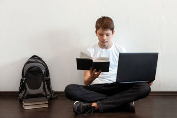 Student sitting on the floor with legs crossed and using laptop. Difficult choice between modern...