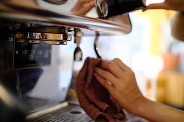 barista woman cleaning professional coffee machine with dust