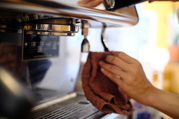 barista woman cleaning professional coffee machine with dust