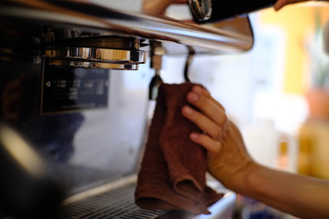 barista woman cleaning professional coffee machine with dust