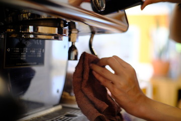 barista woman cleaning professional coffee machine with dust