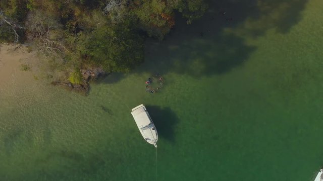 Aerial footage of friends forming a circle in the water of Scotland Bay, Trinidad