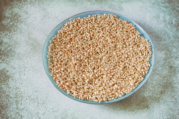 Germinated green buckwheat in a light blue plate on a vintage table. Seed germination. Healthy eating. Sprouted green buckwheat seeds. Selective focus