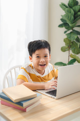 Asia preteen boy studying online on laptop with smiling and fun face at home. online education and e-learning concept.