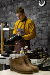 A young man is engaged in Shoe repair. Shoe workshop. The photo illustrates a small business