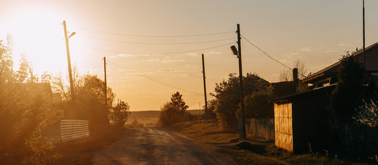 Fototapeta na wymiar Beautiful rural panoramic landscape at sunset. Wooden houses, iron garage and wooden poles. | KOROVYAKOVA, SVERDLOVSKAYA OBLAST - 9 MAY 2020.