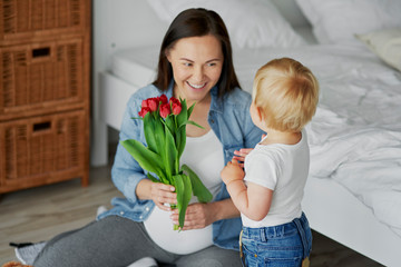 Toddler boy giving his mom a bunch of tulips