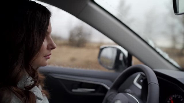 Brunette woman driver behind the steering wheel driving her crossover suv car