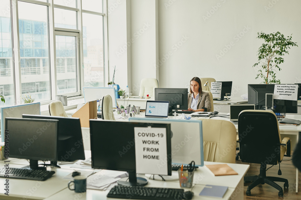 Aufkleber one serious woman sitting in empty office during coronavirus quarantine and preparing report on comp