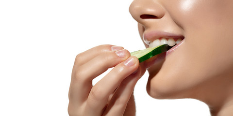 Close up of beautiful young woman with cucumber's slice over white background. Concept of cosmetics, makeup, natural and eco treatment, skin care. Shiny and healthy skin, fashion, healthcare.