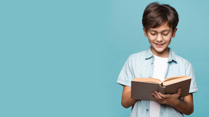 Smiling young boy reading book